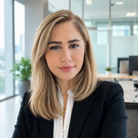 Woman in a black blazer and white blouse posing in a bright modern office.